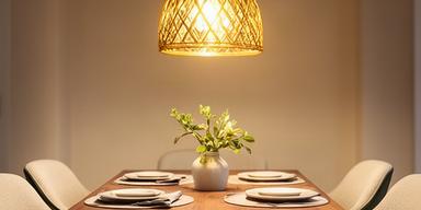 Luminaria de acento colgante sobre mesa de comedor iluminando con tono dorado un ambiente familiar