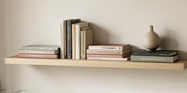 Repisa flotante con libros y pequeño jarrón decorativo en pared de living minimalista